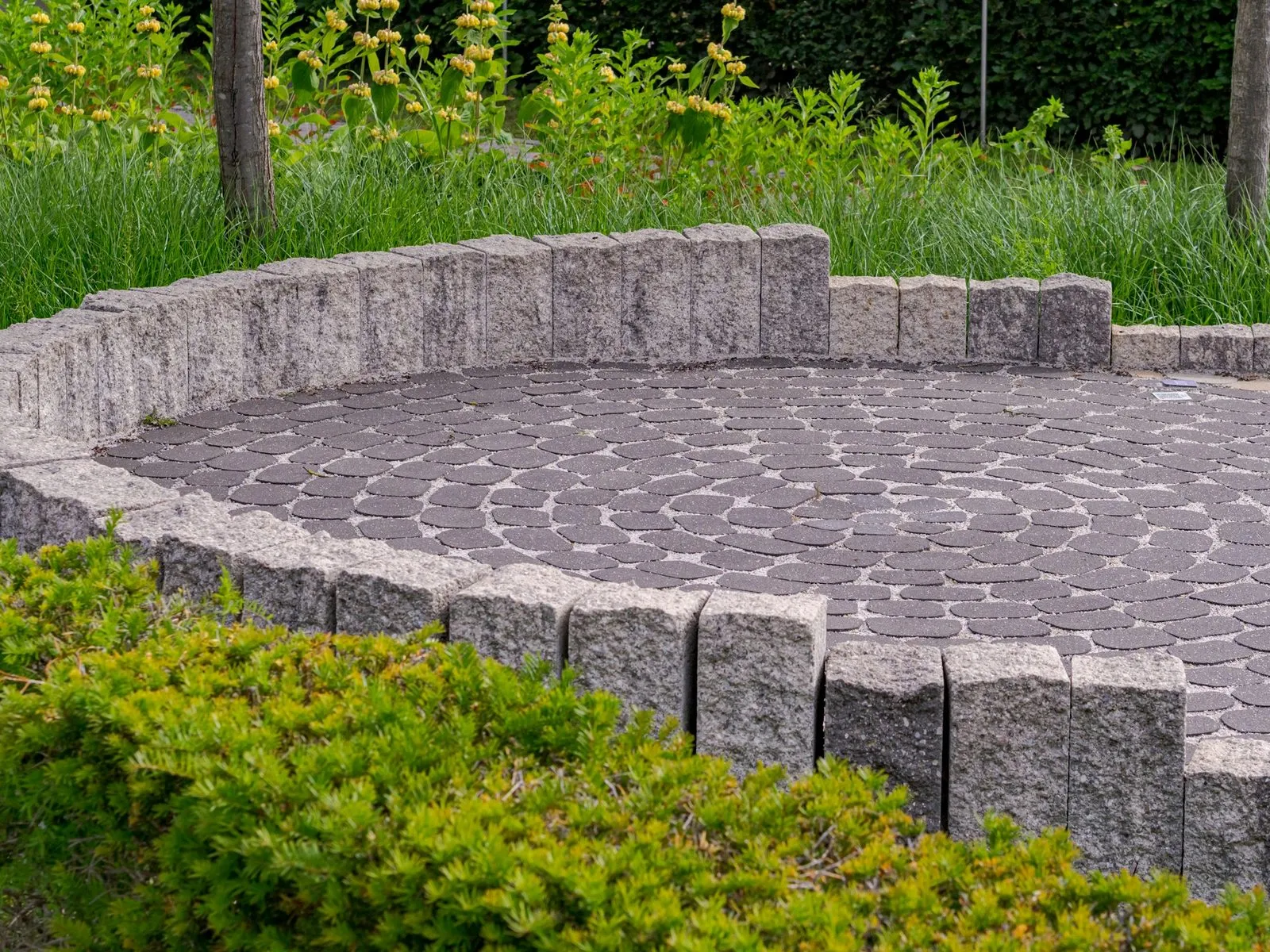 Circular paved seating area edged with a low stone wall